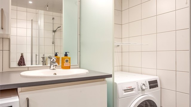 Vegghengt servantinnredning og speil med overlys.