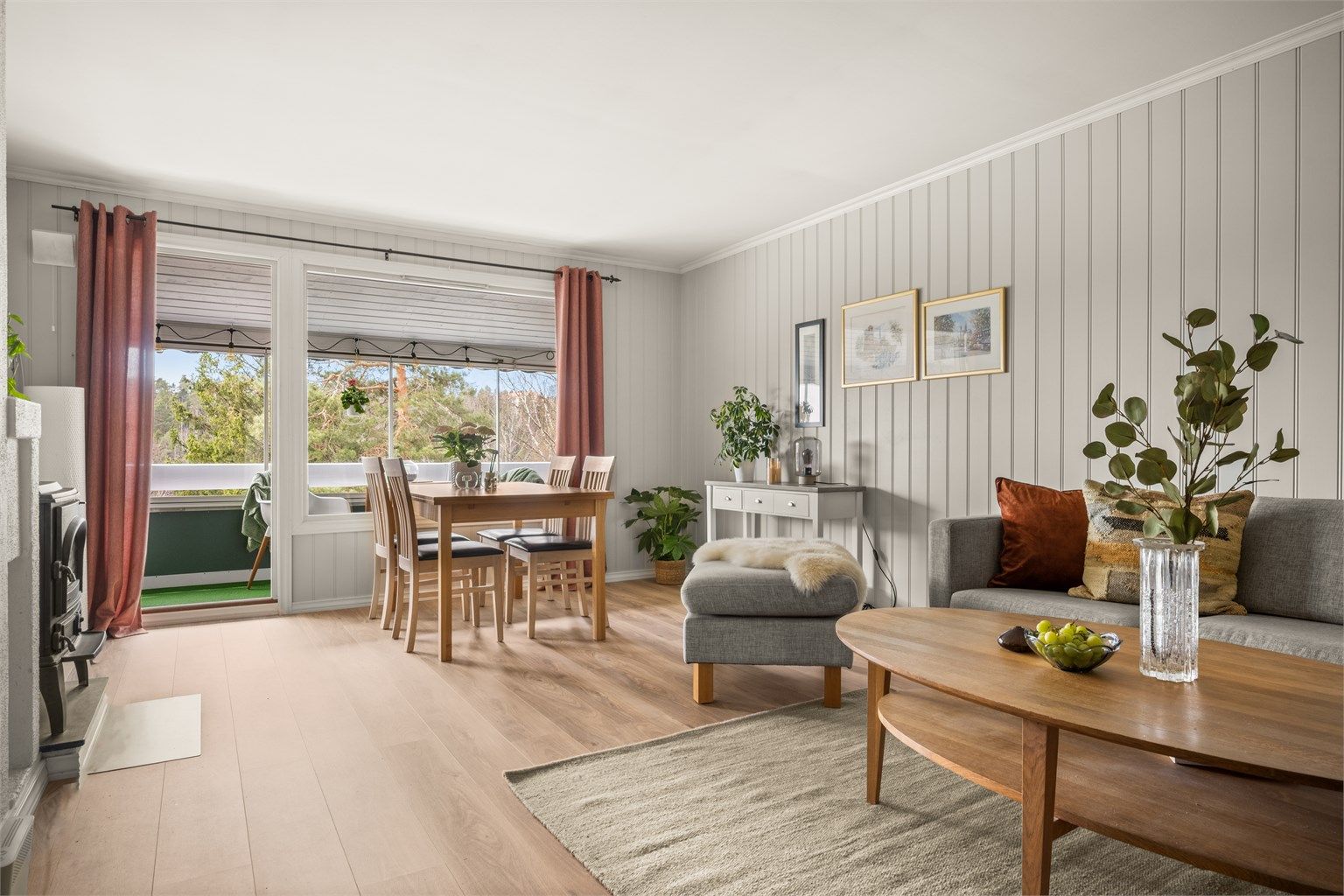 Stuen har god plass til både sofagruppe og spisebord, med naturlig lys fra de store vindusflatene mot verandaen.