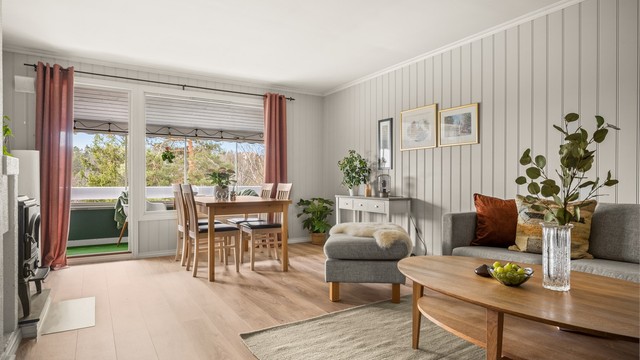 Stuen har god plass til både sofagruppe og spisebord, med naturlig lys fra de store vindusflatene mot verandaen.