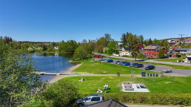 Langvannet ligger en kort spasertur unna med gode bademuligheter på sommerstid. Her kan du skimte bygget til leiligheten i enden av Langvannet gjennom løvbuskene.