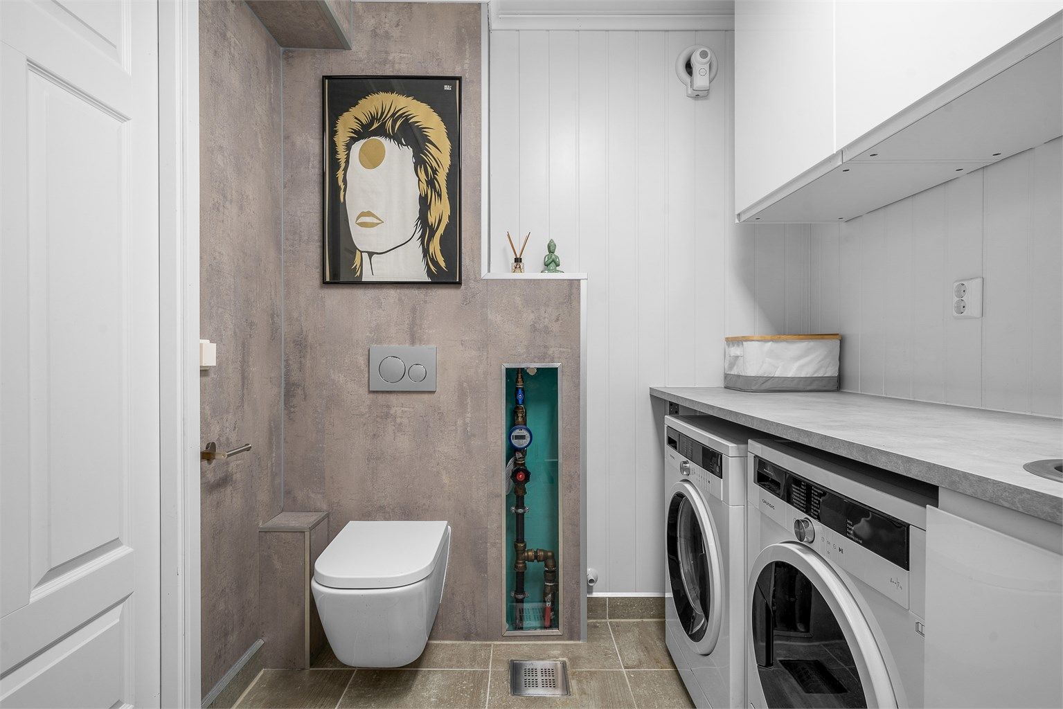 Rommet er funksjonelt innredet med opplegg for vaskemaskin og tørketrommel, og vegghengt toalett.