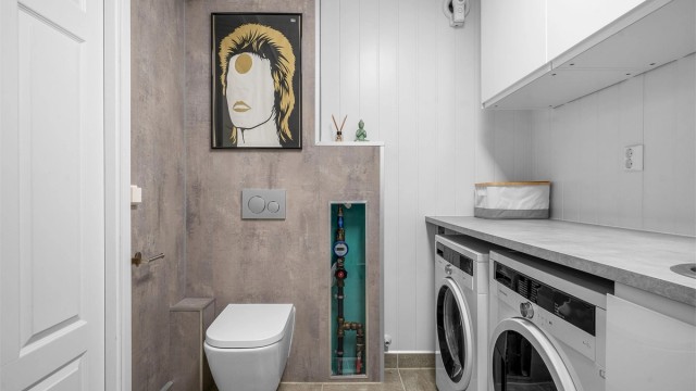 Rommet er funksjonelt innredet med opplegg for vaskemaskin og tørketrommel, og vegghengt toalett.