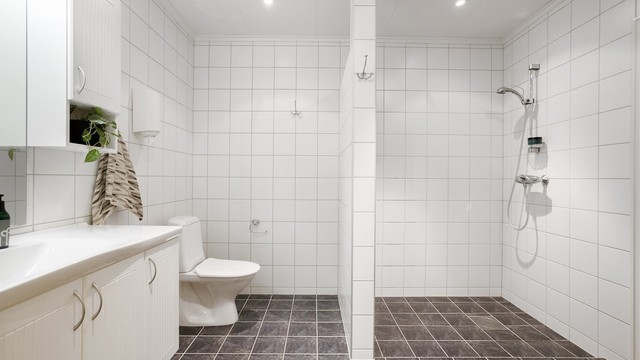 Flislagt bad i sokkeletasjen med varmekabler, servantskap og innfelt belysning.