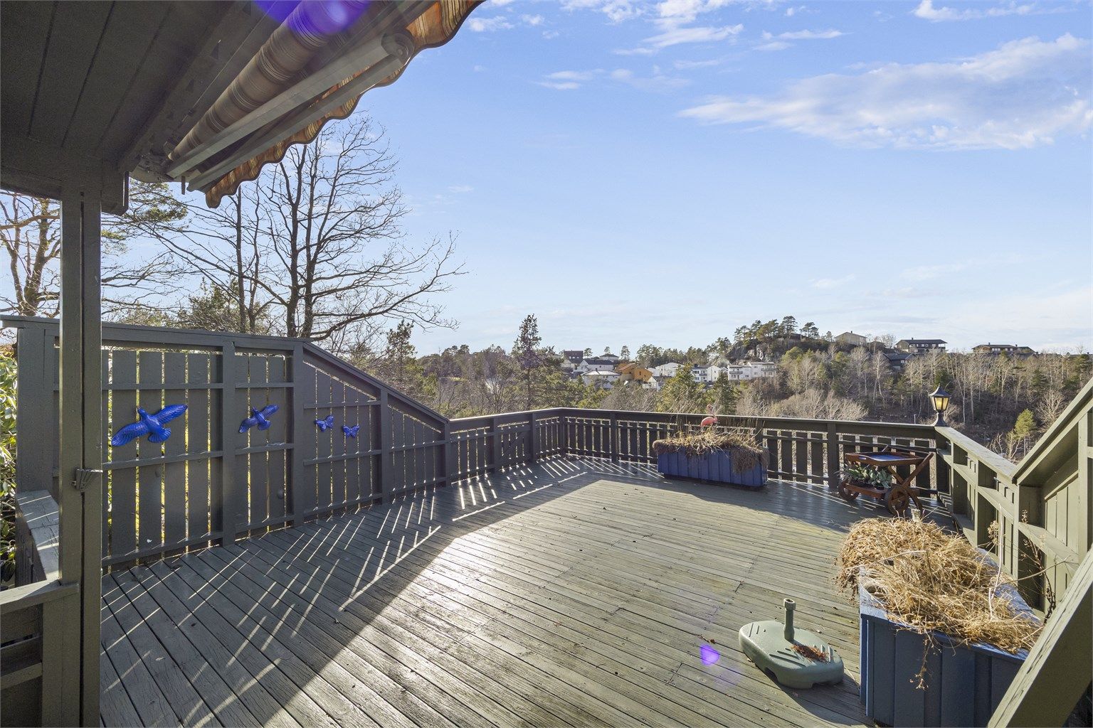 Verandaen har fri utsikt beliggende på kanten. Eiendommens uteområder er usjenerte omringet av diverse busker/trær og verandarekkverk.