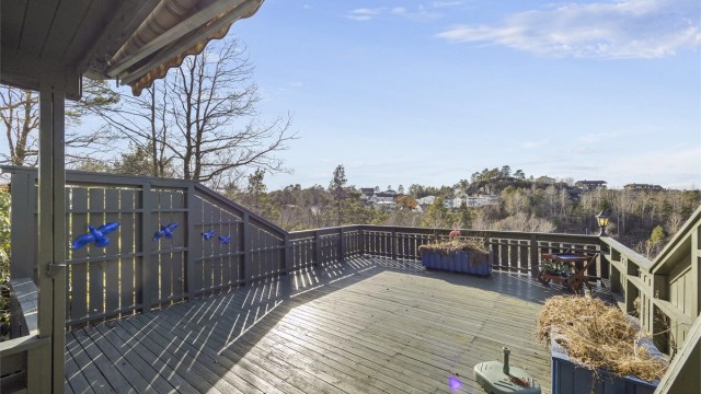 Verandaen har fri utsikt beliggende på kanten. Eiendommens uteområder er usjenerte omringet av diverse busker/trær og verandarekkverk.