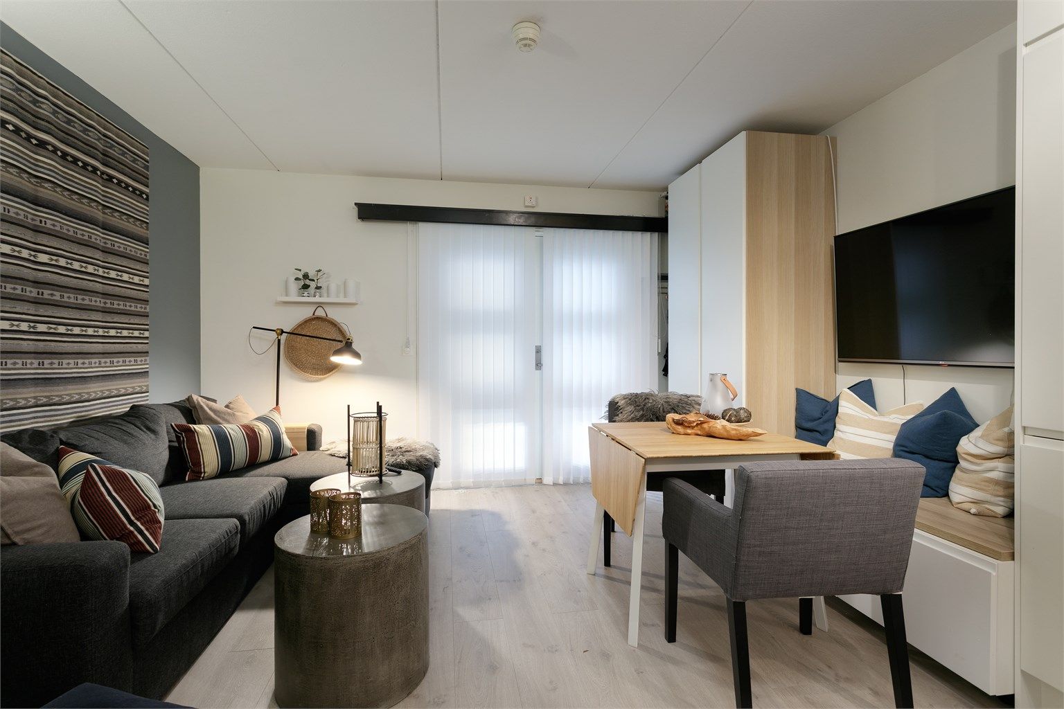 Stue og kjøkken i åpen løsning med plassbygd skap og sittebenk med gode oppbevaringsmuligheter