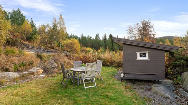 En skjermet og naturnær uteplass hvor du kan nyte rolige dager i vakre omgivelser. Her finner du også eiendommens redskapsbod.
