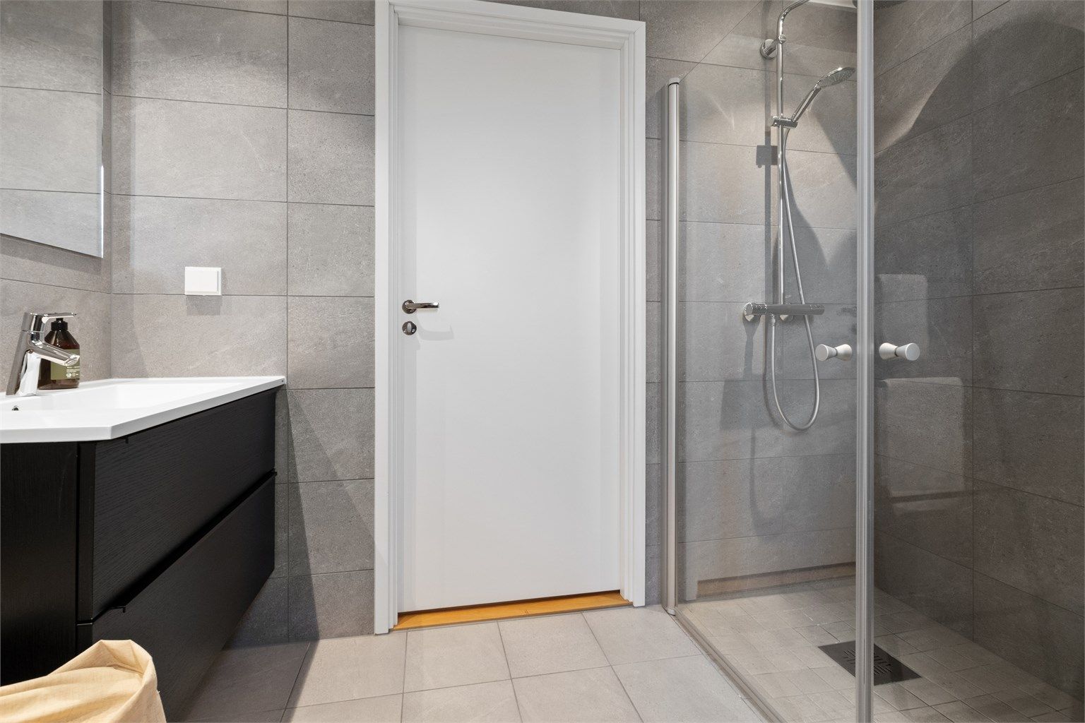 Begge badene har pene, grå fliser på veggene, downlights i himlingen og lyse fliser på gulv med elektrisk gulvvarme.