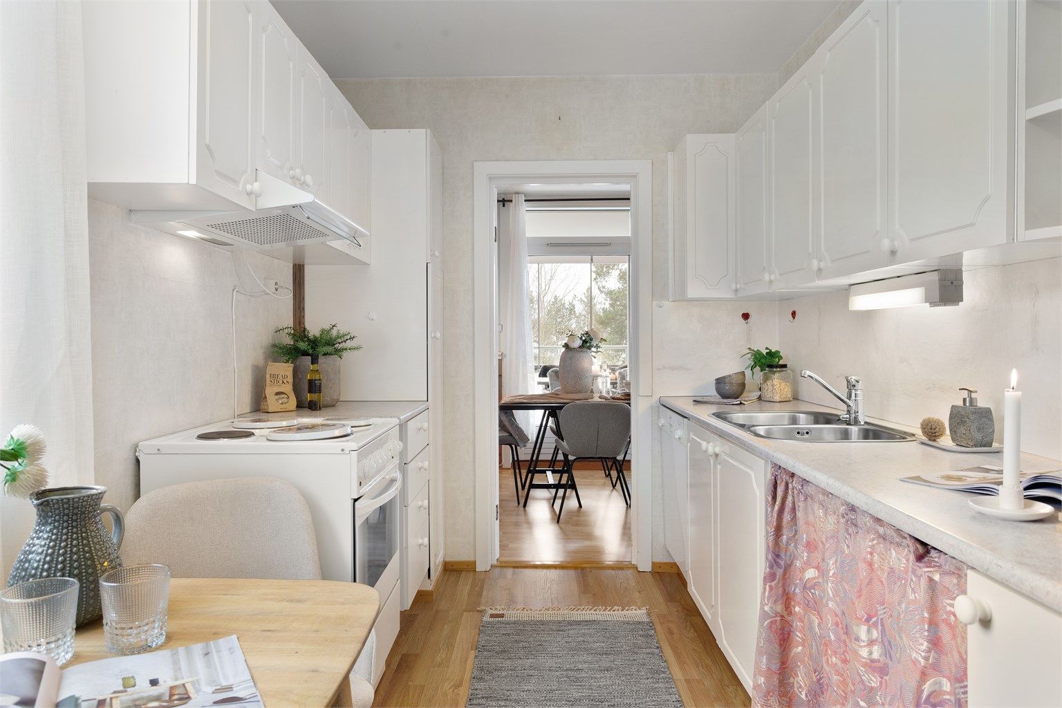 Kjøkken med innredning med hvite profilerte fronter. Benkeplate i laminat med nedfelt oppvaskkum i stål