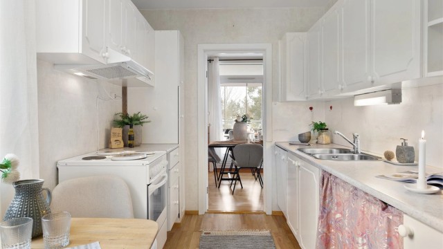 Kjøkken med innredning med hvite profilerte fronter. Benkeplate i laminat med nedfelt oppvaskkum i stål