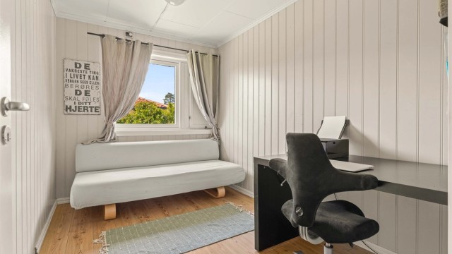 Ett av tre soverom i boligens første etasje. Rommet har laminatgulv og malte panelplater.