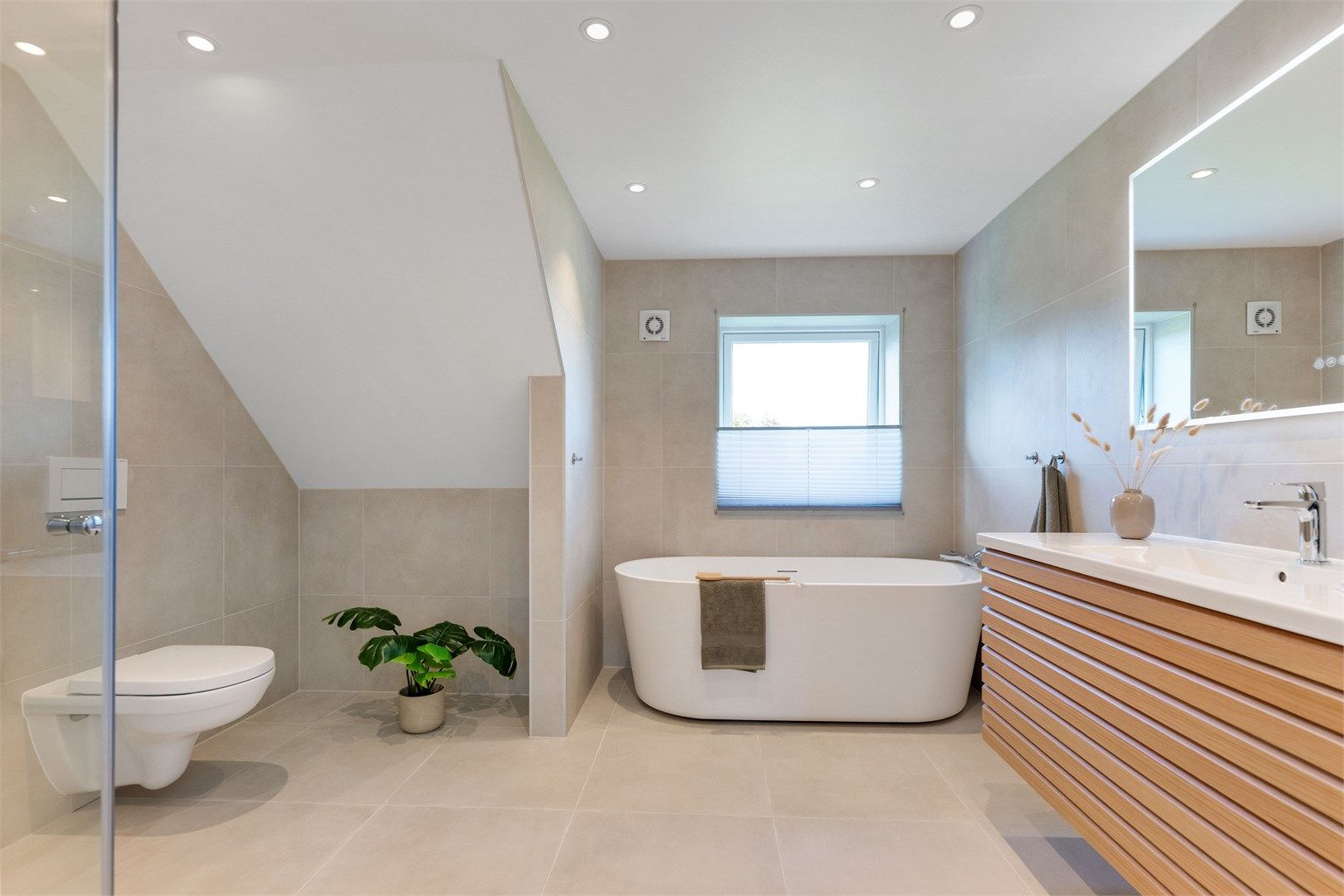 Badet fremstår som svært innbydende med store fliser, lekker innredning, frittstående badekar og eksklusiv hotellfølelse.