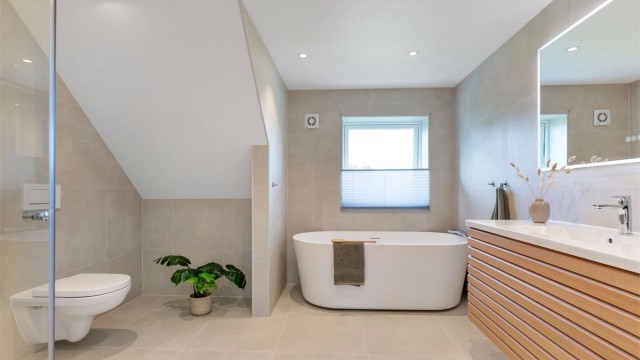 Badet fremstår som svært innbydende med store fliser, lekker innredning, frittstående badekar og eksklusiv hotellfølelse.