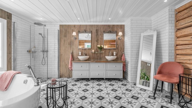 Badet har flislagt gulv med varmekabler, veggene er kombinasjon av originale tømmervegger, flislagte vegger, og malte himlingsflater med downlights