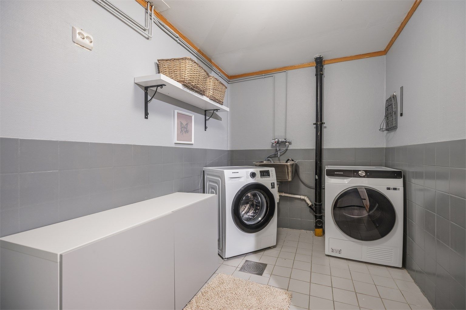 Praktisk vaskerom med utslagsvask i rustfritt stål samt god plass til vaskemaskin og tørketrommel. 