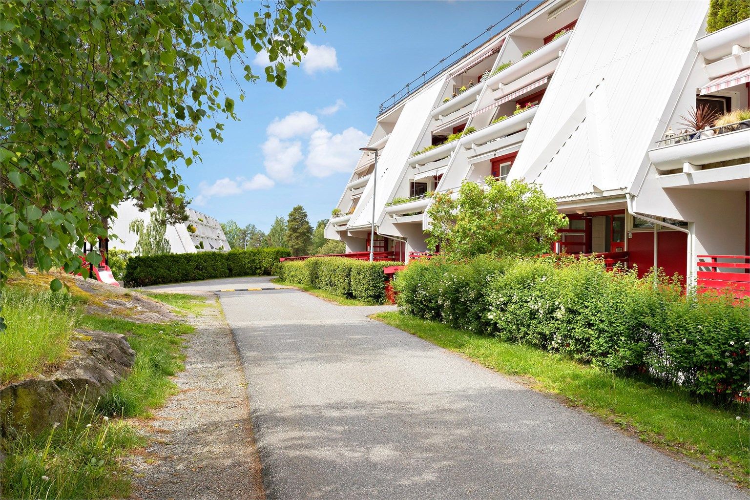 Sommerbilde ved inngangspartiet med pent opparbeidet uteareal