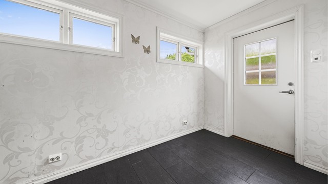 Romslig og innbydende entrè med flislagt gulv med varmekabler.