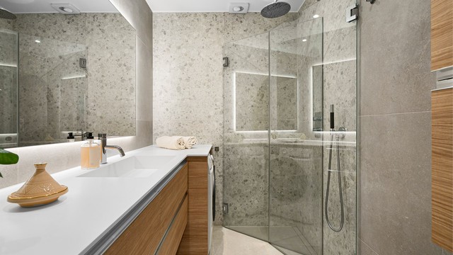 Badet er innredet med servantinnredning med ovenpåliggende vask og speil over vasken. Videre er det egen dusjsone med glassdør og innebygget dusjarmatur.