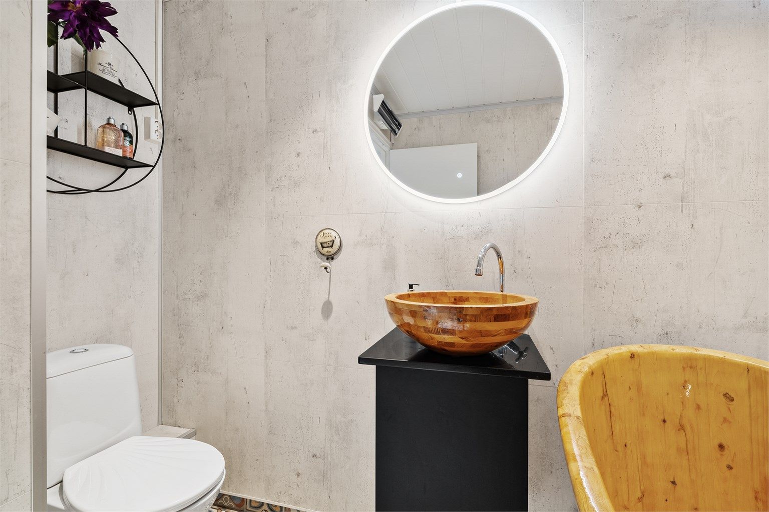 Badet er innredet med badekar, gulvstående toalett, baderomsinnredning og speil med integrert lys. 