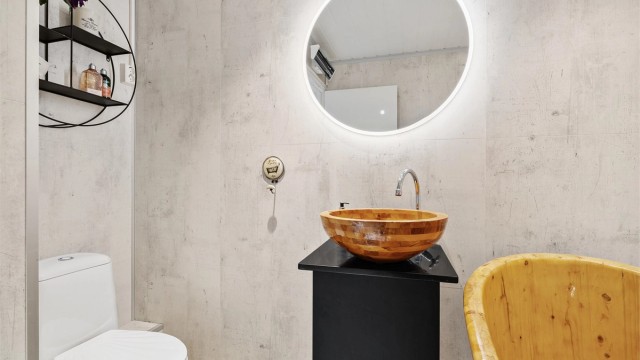 Badet er innredet med badekar, gulvstående toalett, baderomsinnredning og speil med integrert lys.