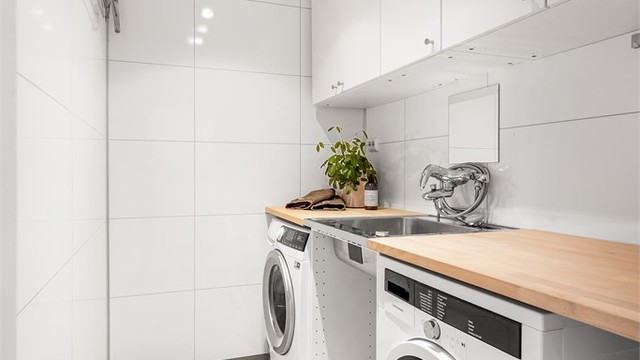 Vaskerom med gulvstående servantinnredning og vegghengte oppbevaringsskap. Opplegg for vaskemaskin.