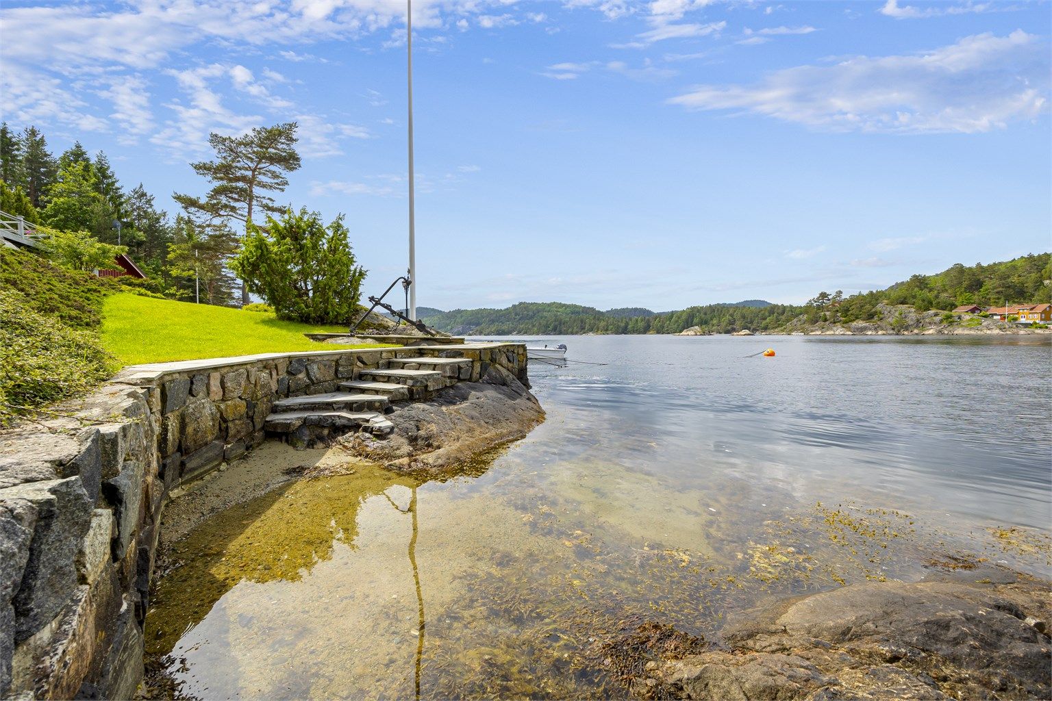 Forstøtningsmurer av naturstein ved plen og brygge. Perfekt sted å bade for store og små.