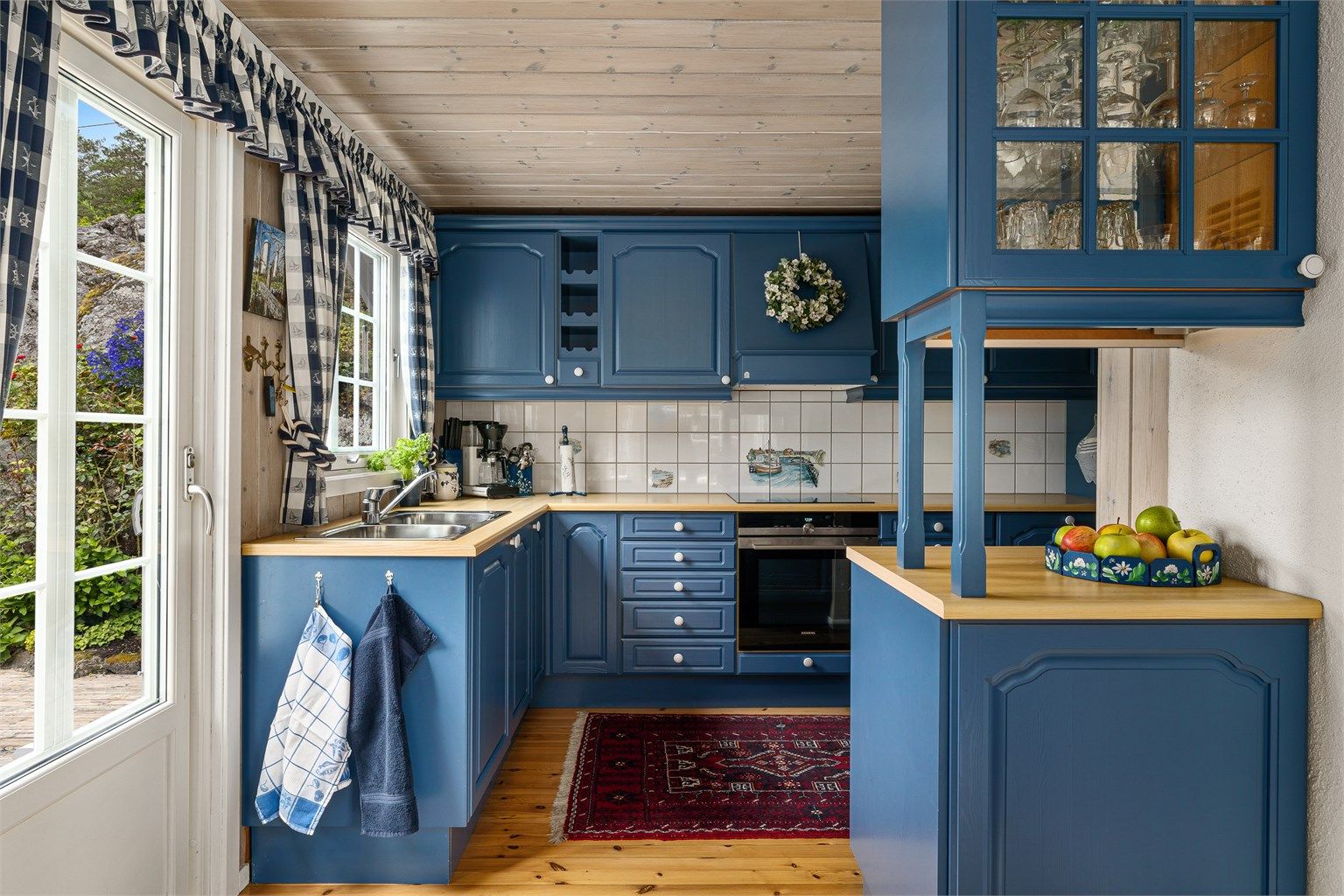 Kjøkkenet i mørk blå står godt til hytta. Innredningen vender mot stua.