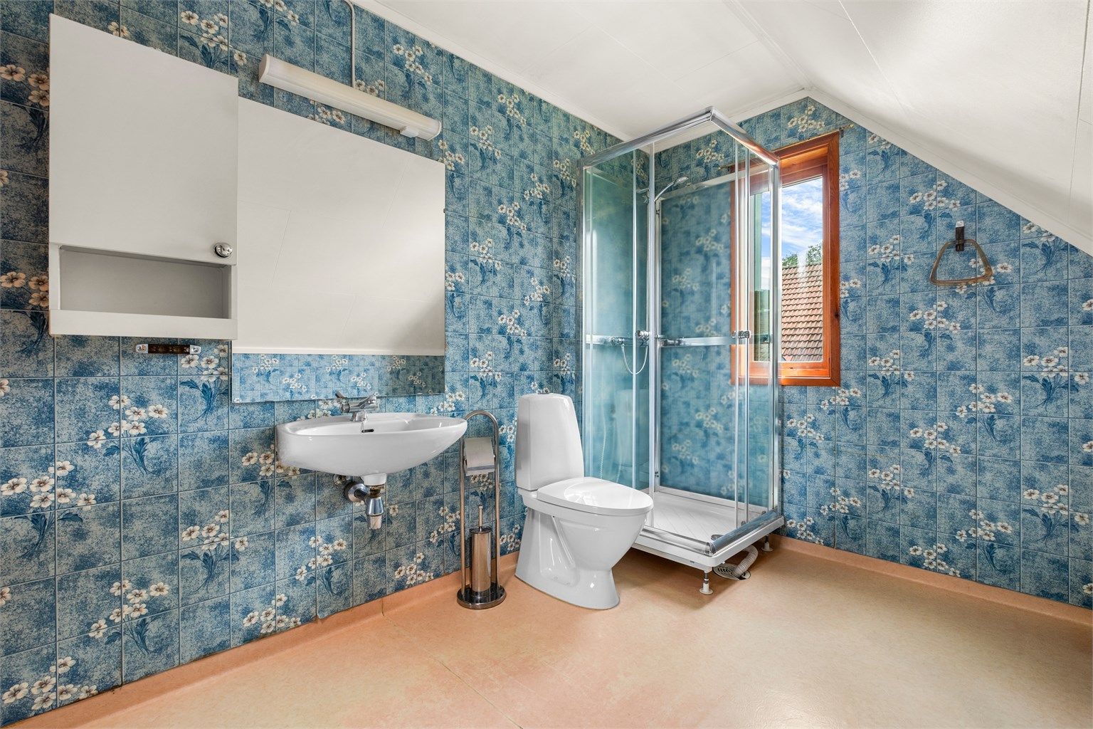 Badet er fra byggeår og er innredet med dusjkabinett, toalett og servant.