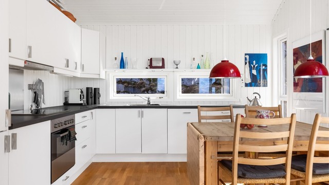 Pent kjøkken med lyse slette flater og benkeplate i kontrast.