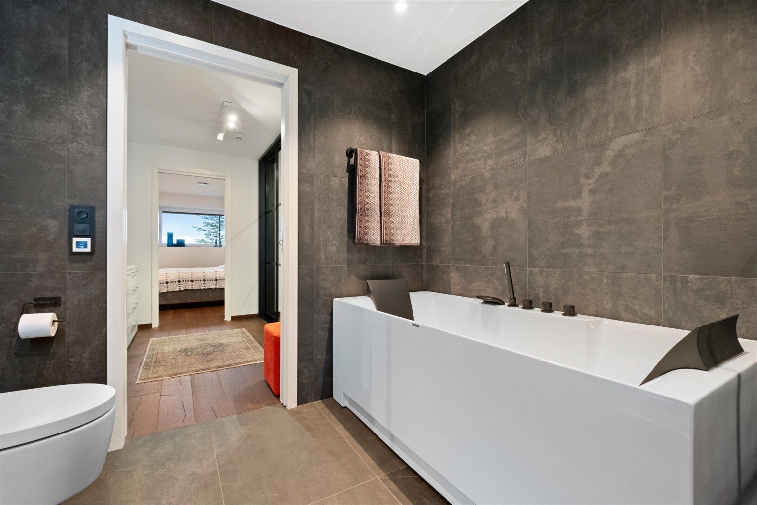 Badet har frittstående badekar med innfelt badekarsarmatur i tillegg til dusjhjørne med glassvegger og vegghengt dusjarmatur med hånddusj og regndusj