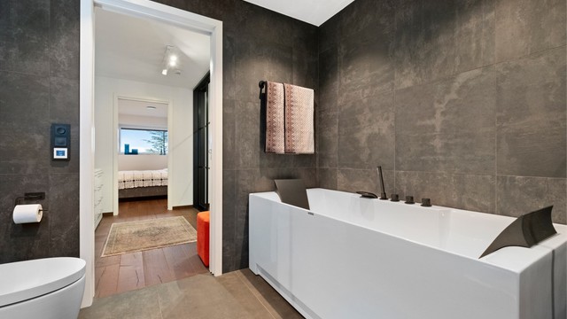 Badet har frittstående badekar med innfelt badekarsarmatur i tillegg til dusjhjørne med glassvegger og vegghengt dusjarmatur med hånddusj og regndusj