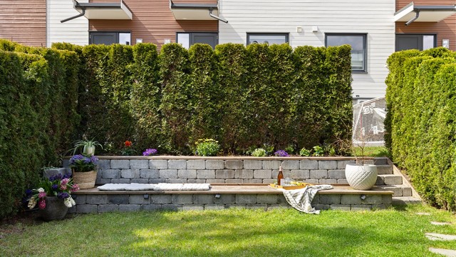 Pent opparbeidet uteplass med blomsterbed, sittebenk i naturstein med integrert belysning, og mulighet til å dekorere med planter og lykter.