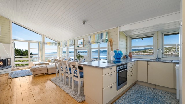 Kjøkkenet ligger naturlig skjermet fra stuen og er innredet lyse slette fronter og benkeplate i kontrast.