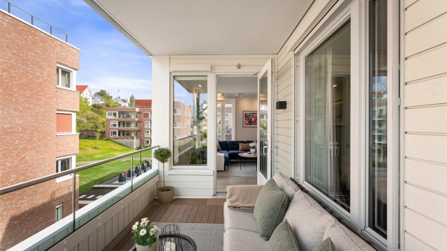 Store vindusflater og dør til balkongen gir rikelig med lys til stuen.