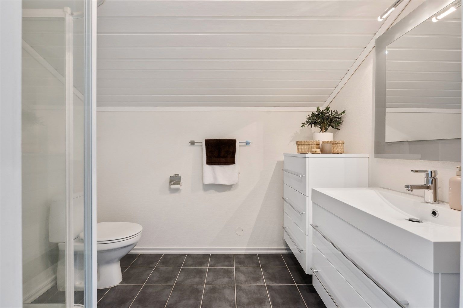 Baderommet i loftetasjen har dusjkabinett og flislagt gulv med gulvvarme.