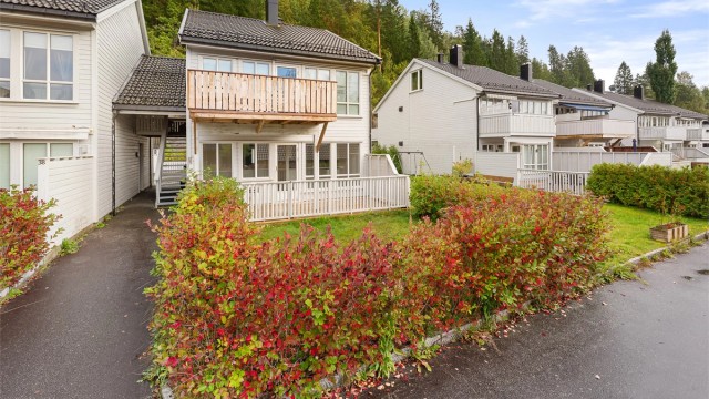 Boligen har et hyggelig inngangsparti med beplantning og fine utearealer.