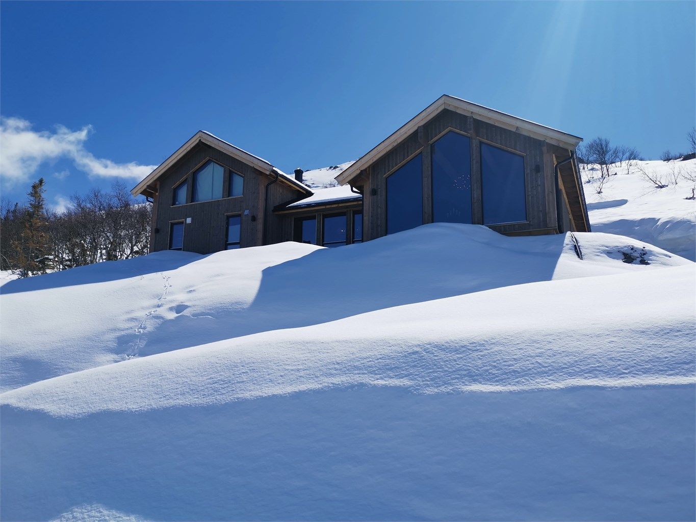 Hytta i vinterdrakt med snørike omgivelser rett utenfor hytteveggen.