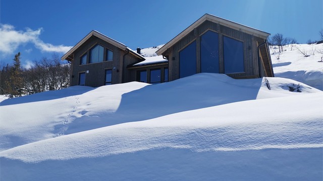 Hytta i vinterdrakt med snørike omgivelser rett utenfor hytteveggen.