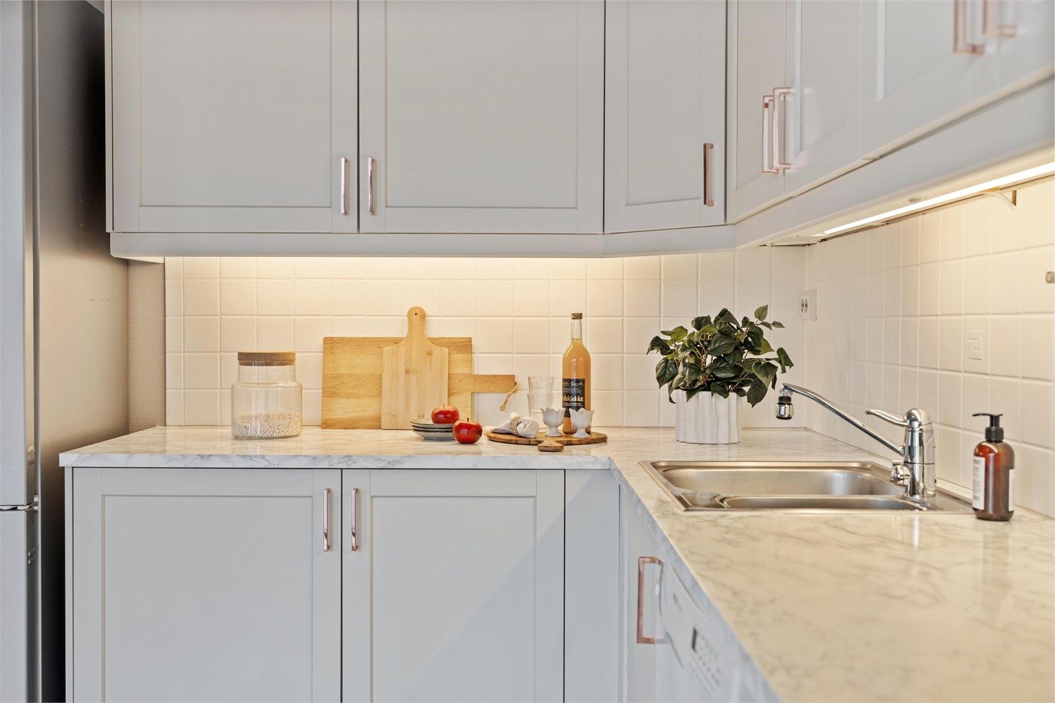 Laminatbenkeplate og fliser over benken gir slitesterke og lettstelte arbeidsflater. God belysning under overskapene.