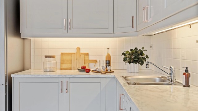 Laminatbenkeplate og fliser over benken gir slitesterke og lettstelte arbeidsflater. God belysning under overskapene.