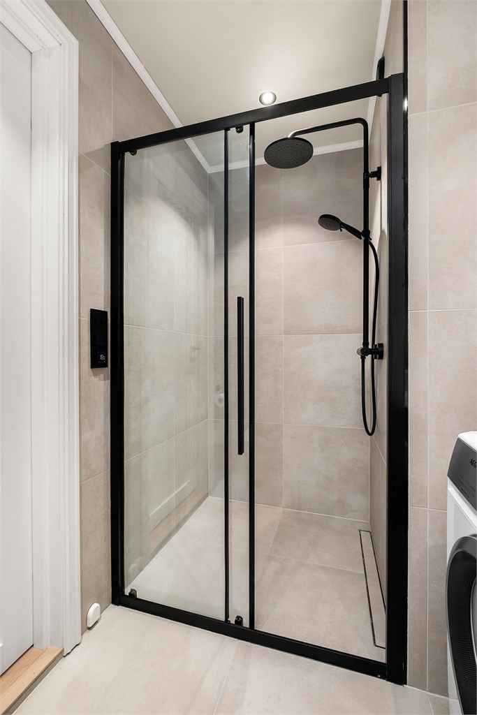 Romslig dusjsone med moderne detaljer og flislagte overflater som understreker badets helhetlige uttrykk.