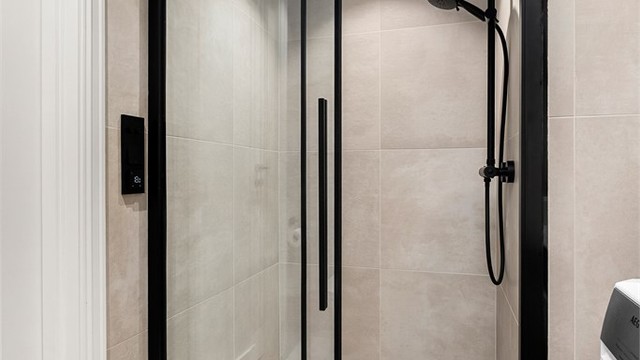 Romslig dusjsone med moderne detaljer og flislagte overflater som understreker badets helhetlige uttrykk.