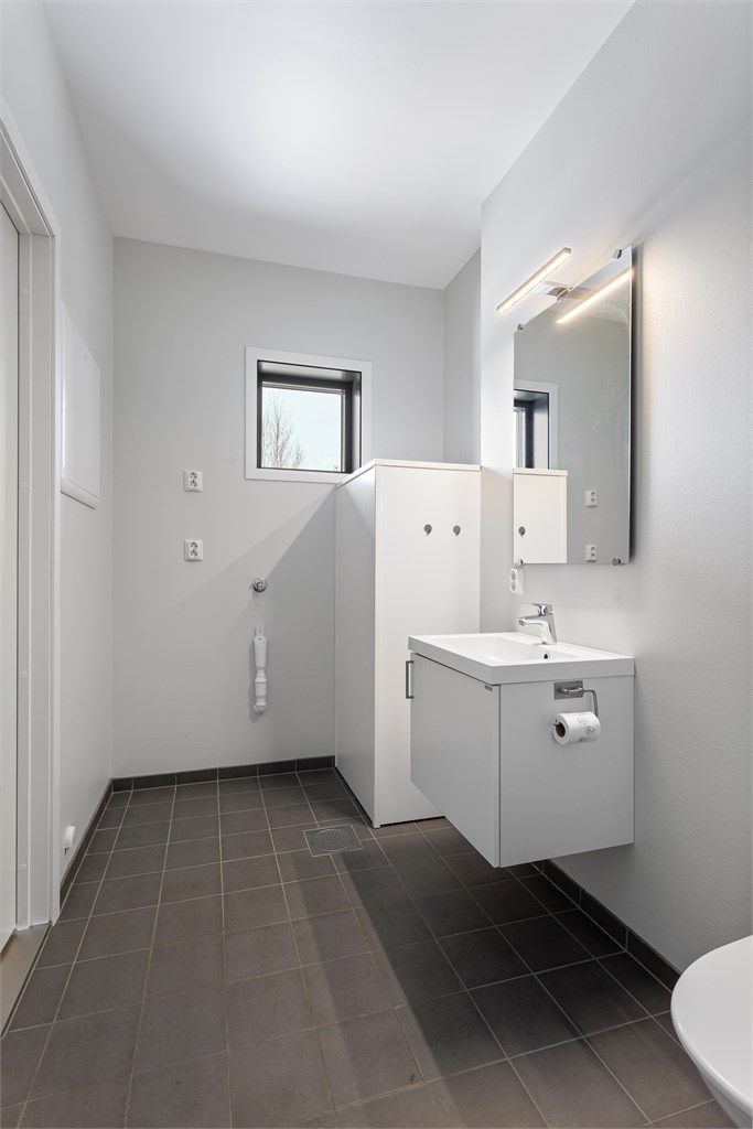 Badet har flislagt gulv med behagelig gulvvarme og praktisk opplegg for vaskemaskin.