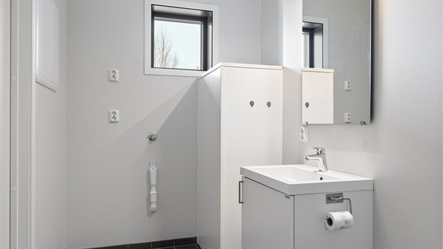 Badet har flislagt gulv med behagelig gulvvarme og praktisk opplegg for vaskemaskin.