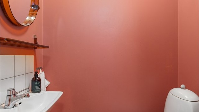 Toalettrom tilknyttet gang malt i spreke farger på vegger og innredet med toalett, servant og speil