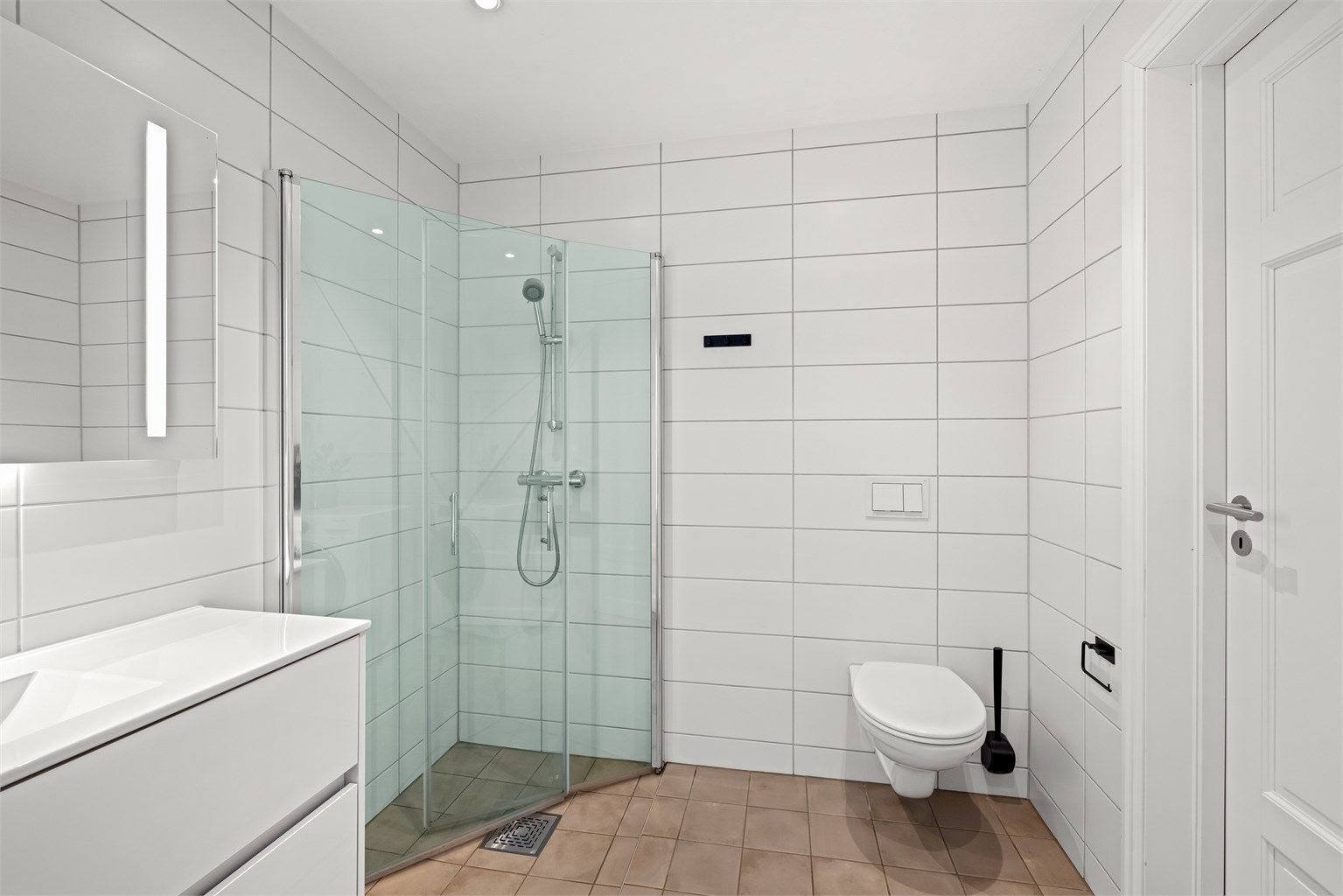 Første etasje har et praktisk, flislagt bad med dusjhjørne og vegghengt toalett. Opplegg for vaskemaskin.