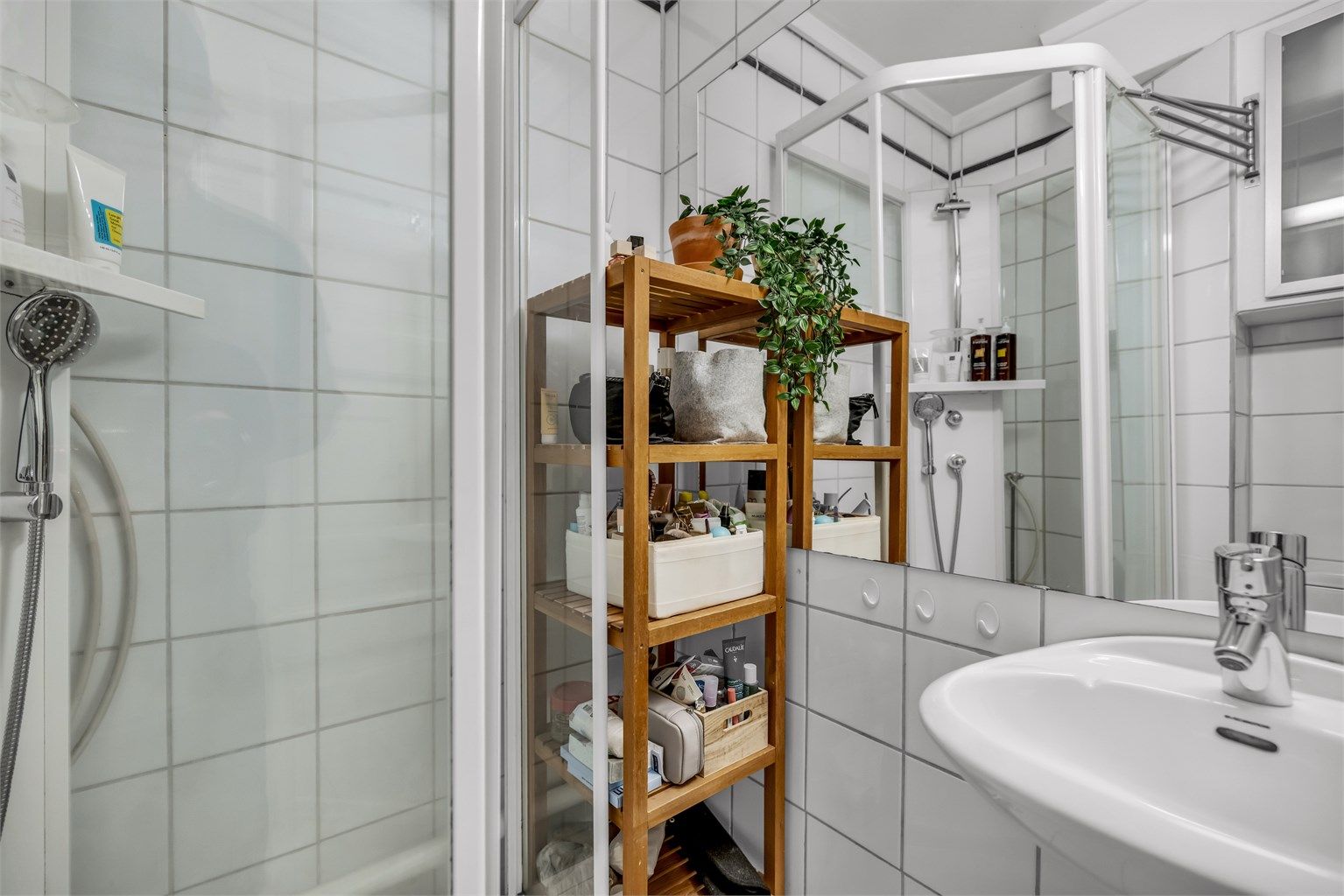 Videre er det gulvstående toalett, dusjkabinett og praktisk vegghengt skap til oppbevaring.