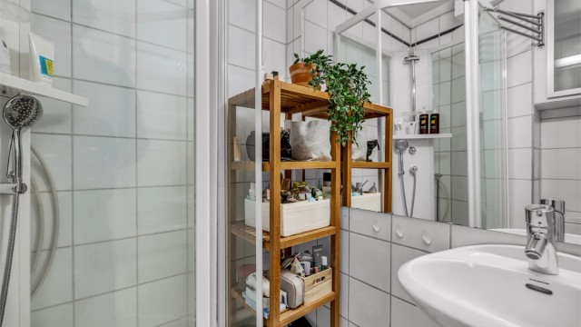 Videre er det gulvstående toalett, dusjkabinett og praktisk vegghengt skap til oppbevaring.
