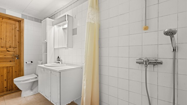 Vegghengt dusjarmatur og naturlig avtrekksventil i himling.