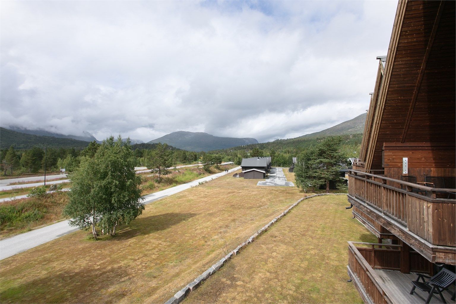 Åpent utsyn mot grøntarealer og fjelltoppene rundt dalen.